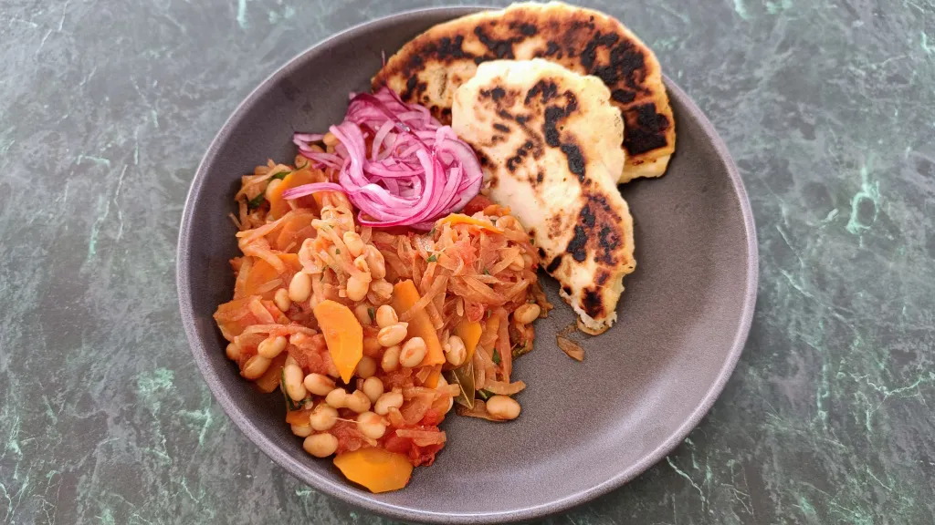 Photograph of Bean stew with cheese flatbreads and pickled onions.