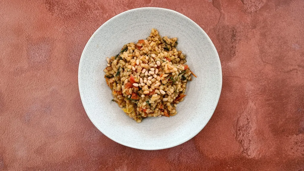 Photograph of Gently spiced pearl barley with tomatoes, leeks, dill & pine nuts.
