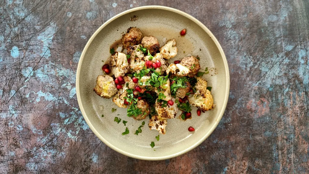 Photograph of Spiced lamb meatballs with sumac roasted cauliflower & pomegranate.